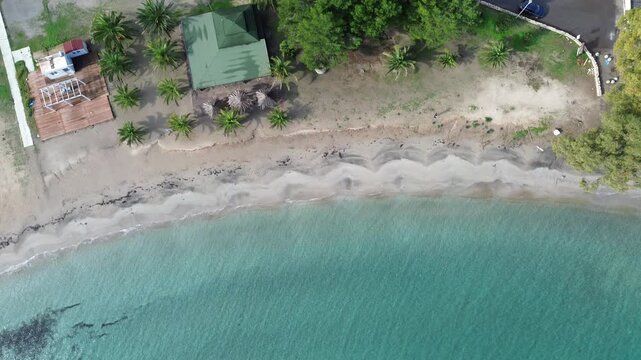 Drone view of Maladroxia&rsquo;s clear turquoise sea, sandy shoreline, and coastal houses.