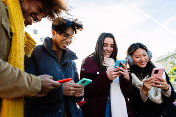 Young group of people in warm clothes using mobile phone device on winter. Social media and...