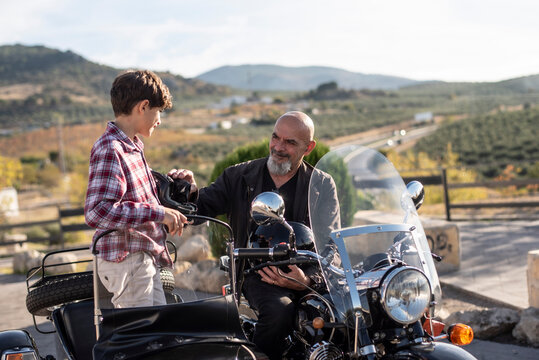 Little boy with his grandfather on sidecar bike.
