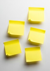 Fototapeta premium Yellow Sticky Notes on White Surface - Five yellow sticky notes adhering to a white surface, symbolizing reminders, memos, ideas, organization, and notes