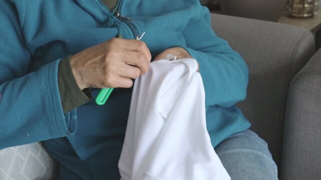 Elderly Woman Hand-Sewing a Shirt at Home