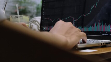 Close-up hand checking a smartwatch while analyzing stock, crypto charts on a laptop. Depicts pressure, time management, and professional trading - Powered by Adobe
