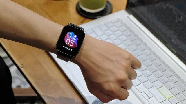 Young student anxiously glances at a smartwatch on his wrist while working, studying. Depicts time pressure, deadlines, and academic stress - Powered by Adobe