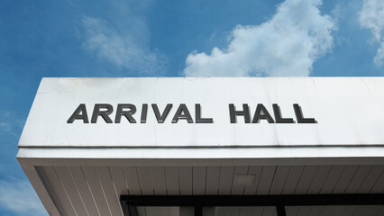 Obraz premium Arrival Hall word sign displayed on building under clear blue sky, representing airport terminals, travel, passenger services, and public facilities