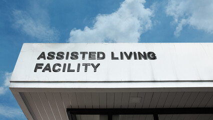 Assisted Living Facility word sign displayed on building under clear blue sky, representing senior care, housing, healthcare, and supportive community services