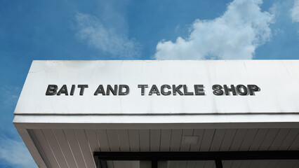 Bait and Tackle Shop word sign displayed on building under clear blue sky, representing fishing supplies, outdoor recreation, and angling equipment