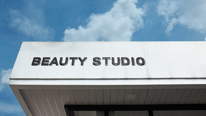 Beauty Studio word sign displayed on building under clear blue sky, representing personal care, cosmetics, hairdressing, and wellness services