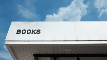 Books word sign displayed on building under clear blue sky, representing reading, literature, education, libraries, and cultural knowledge