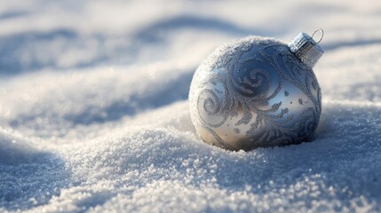 Silver Christmas ornament resting in fresh, sparkling snow on a sunny day