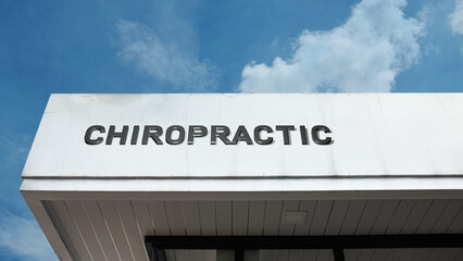 Chiropractic word sign displayed on a building under a clear blue sky, representing spinal care, health services, therapy, wellness, and medical treatment facilities