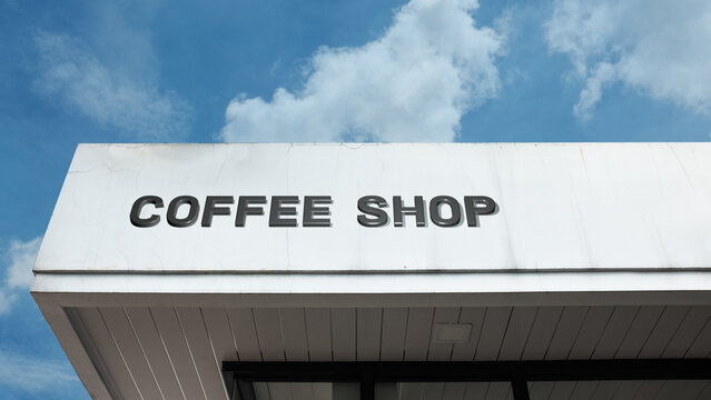 Coffee Shop word sign displayed on a building under a clear blue sky, representing café culture, beverages, socializing, leisure, and hospitality facilities - Powered by Adobe
