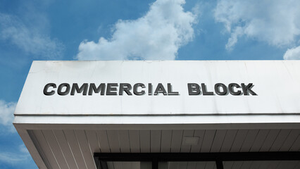 Obraz premium Commercial Block word sign displayed on a building under a clear blue sky, representing retail, business, offices, commerce, and urban development facilities