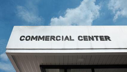 Obraz premium Commercial Center word sign displayed on a building under a clear blue sky, representing retail, business, offices, commerce, and urban development facilities
