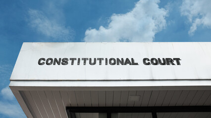 Obraz premium Constitutional Court word sign displayed on a building under a clear blue sky, representing judiciary, legal authority, government, law, and public administration facilities