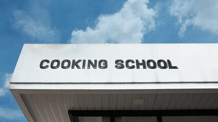 Cooking School word sign displayed on a building under a clear blue sky, representing culinary education, professional training, gastronomy, and kitchen facilities