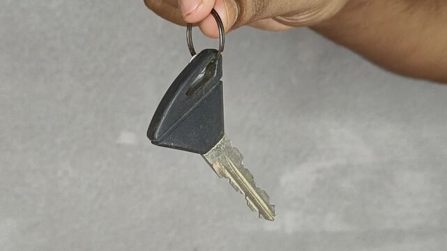 Hand holding keys against white background with copy space. Simple gesture symbolizes access, security, homeownership for real estate, automotive, and property concepts.