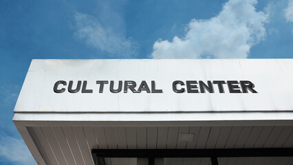 Obraz premium Cultural Center word sign displayed on a building under a clear blue sky, representing arts, heritage, community events, education, creativity, and public engagement