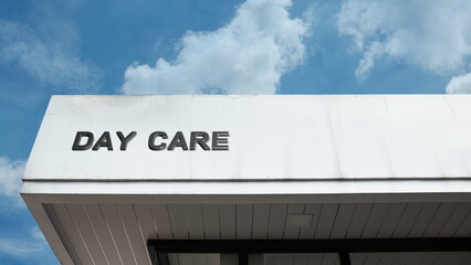 Day Care word sign on a building under a clear blue sky, representing childcare, learning, play, development, safety, education, and community activities