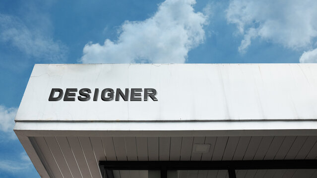 Designer word sign on a building under a clear blue sky, representing creativity, fashion, design work, professional services, and artistic expertise - Powered by Adobe