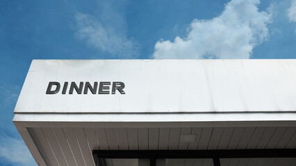 Dinner word sign displayed on a building under a clear blue sky, symbolizing food, dining, meals, and a space for gatherings, social events, and shared meals.