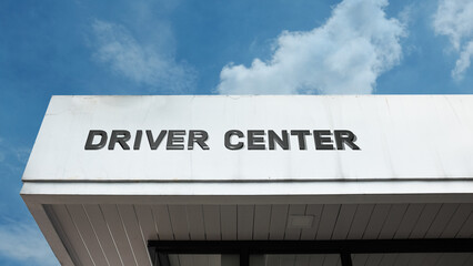 Driver center word sign displayed on a building with blue sky background, highlighting services related to driving, training, or vehicle expertise.