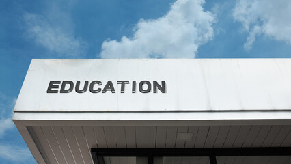 Education word sign displayed on a building with a blue sky background, representing academic services, learning, and educational institutions.