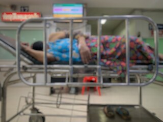 An elderly female patient lies in a wheelchair in a hospital.