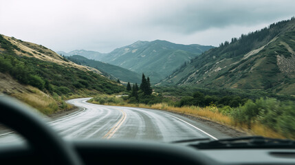 POV driving on wet winding mountain road through green valley in rain