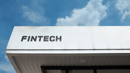 Fintech sign displayed on a building against a clear blue sky, symbolizing financial technology, digital banking, innovation, commerce, software, and economic disruption