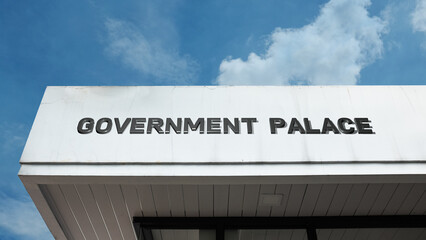 Obraz premium Government Palace sign displayed on a building against a clear blue sky, symbolizing national leadership, official residence, executive power, historic landmark, and political center