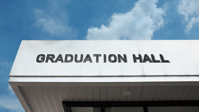 Graduation Hall sign displayed on a building against a clear blue sky, symbolizing academic ceremony, achievement, commencement, educational institution, and milestone event