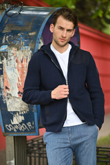A close-up of a man adjusting the zipper of his navy hoodie. Focus on texture, fabric quality, and simple everyday style.
