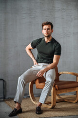 A standing portrait of a man in a green T-shirt, leaning casually against modern staircase rails. Minimalist surroundings enhance his confident stance and clean casual aesthetic.