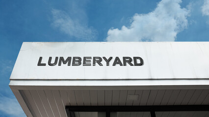 Naklejka premium Lumberyard sign on a building against a clear blue sky, symbolizing wood retailer, construction material, building supply, timber storage, and trade
