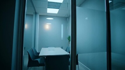 Dimly lit meeting room, modern minimalist design with glass walls, corporate workspace during late hours, office environment and after-hours vibe