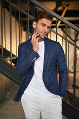 A man in a blazer sits on a chair with warm sunlight illuminating the scene, creating a calm and sophisticated editorial mood.