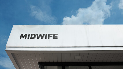 Midwife sign on a building against a clear blue sky, symbolizing maternity care, professional birth assistance, healthcare, women's services, and obstetrics