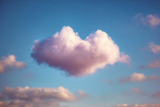 Heart-shaped pink cloud floating in blue sky