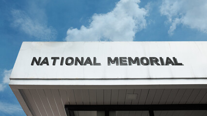 Obraz premium National Memorial sign on a building against a clear blue sky, symbolizing historical remembrance, public tribute, solemn commemoration, national heritage, and landmark