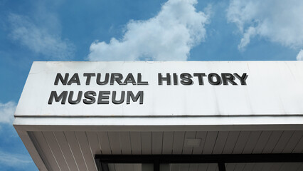 Obraz premium Natural History Museum signage on a grand building under a blue sky, symbolizing science, discovery, education, and cultural history research