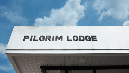 Pilgrim Lodge word signage on a hospitality building under a blue sky, symbolizing religious travel, retreat, spiritual journey, accommodation, and community