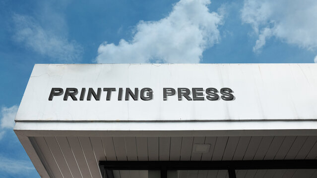 Printing Press word signage on a large industrial building under a blue sky, symbolizing publishing, manufacturing, media production, and mass communication