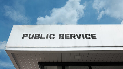 Obraz premium Public Service word signage on a government building under a blue sky, symbolizing civic administration, government work, citizen support, official duties, and bureaucracy