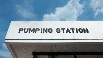 Obraz premium Pumping Station word signage on an industrial or utility building under a blue sky, symbolizing water infrastructure, sewage management, fluid transport, and utility service