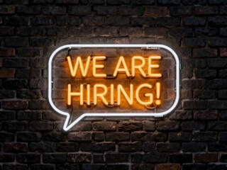 Bright neon sign saying We are hiring glowing on a dark brick wall perfect for attracting job applicants