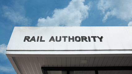 Obraz premium Rail Authority word signage on a government or transport building under a blue sky, symbolizing railroad administration, infrastructure, transportation policy, and official regulation