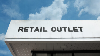 Obraz premium Retail Outlet word signage on a commercial or sales building under a blue sky, symbolizing commerce, point of sale, consumer shopping, distribution channel, and discount store