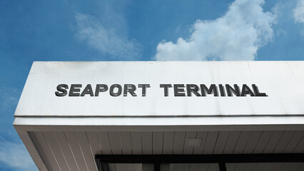 Obraz premium Seaport Terminal word signage on a transit or port building under a blue sky, symbolizing maritime travel, shipping, logistics, international trade, passenger services, and waterfront infrastructure