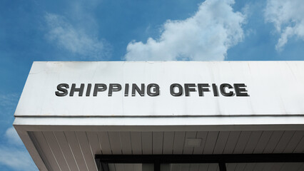 Obraz premium Shipping Office word signage on a logistics or corporate building under a blue sky, symbolizing maritime business, freight management, global transport, supply chain coordination, and commercial opera