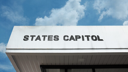 Obraz premium States Capitol word signage on a government or institutional building under a blue sky, symbolizing multiple state governance, legislative action, democracy, politics, federalism